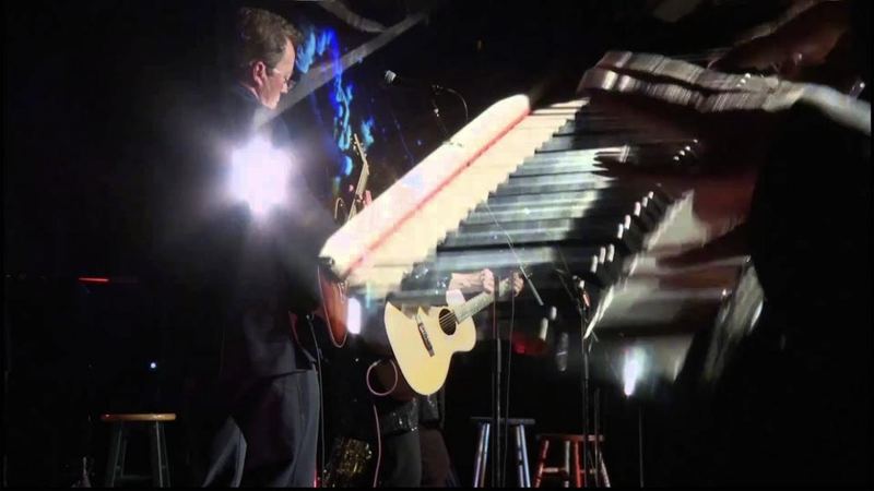 Musicians on a dark stage under bright lights